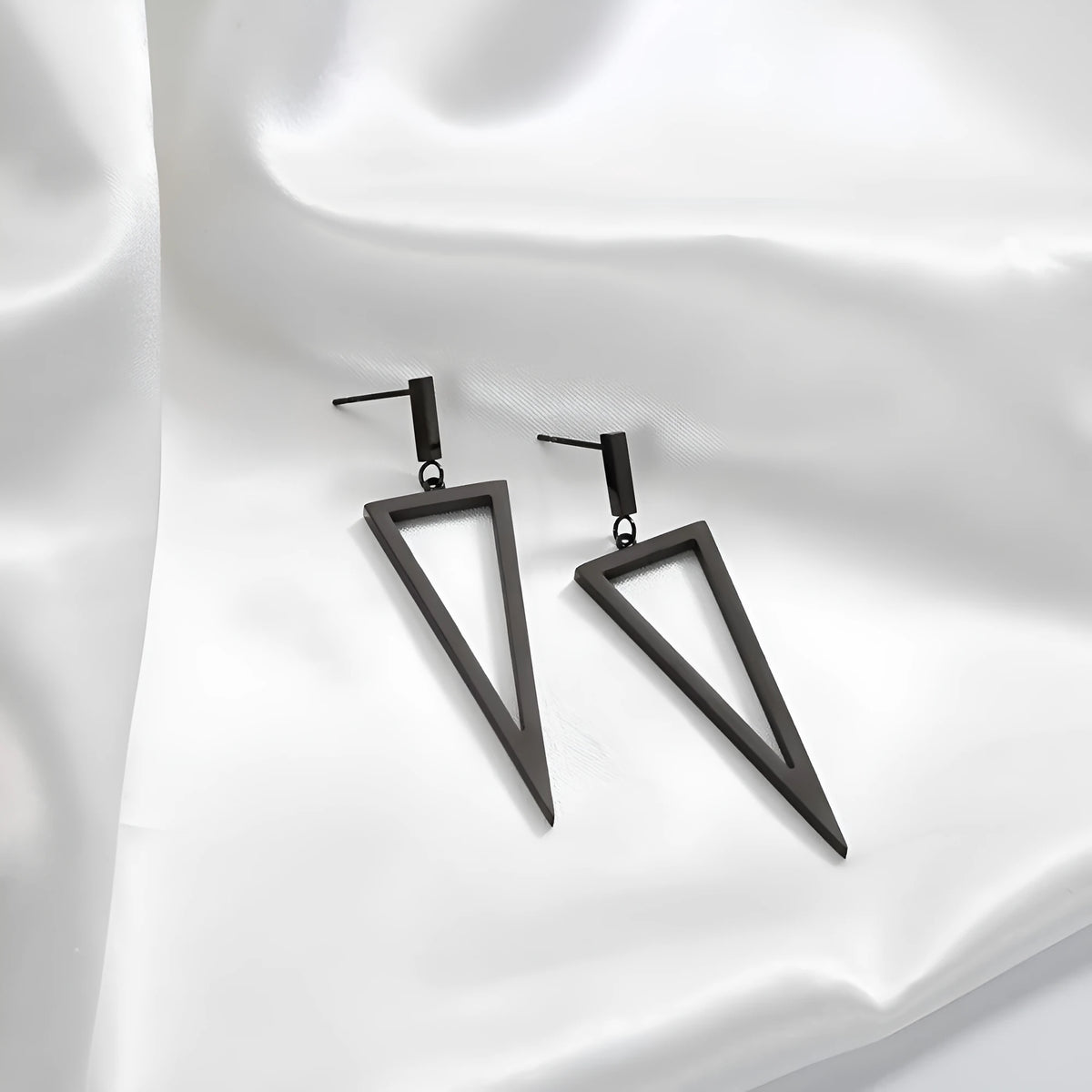 Black metal triangle earrings with electroplated finish on a neutral background