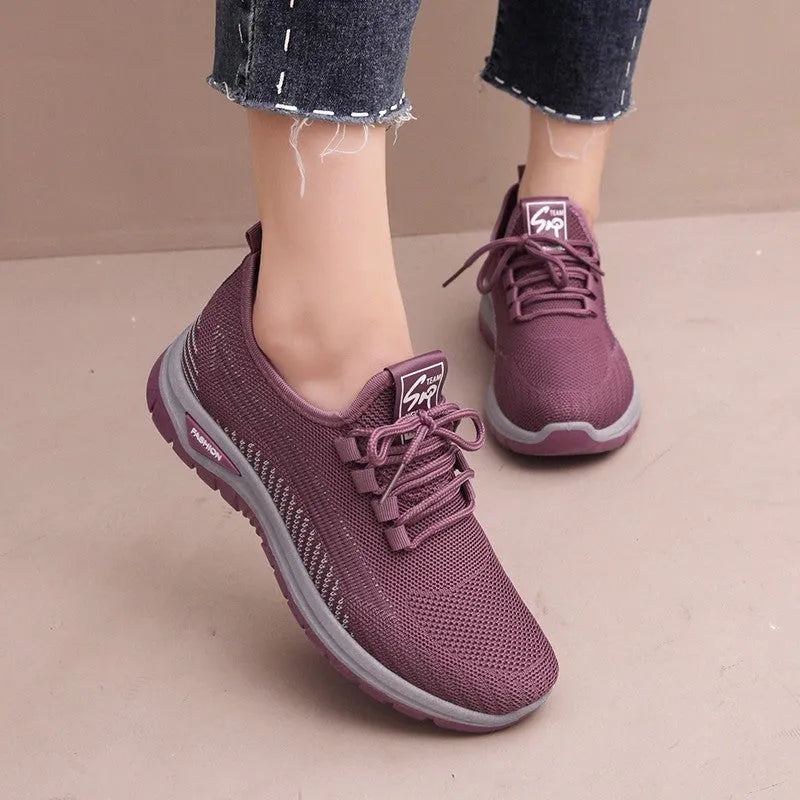 Women's black mesh sneakers with a cross-strap design and round toe, shown on a white background.