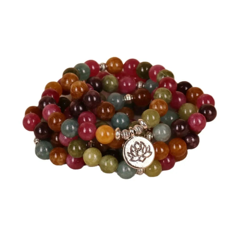 Close-up of a Tourmaline-coloured alloy bracelet with 108 beads and a central hanging lotus decoration.