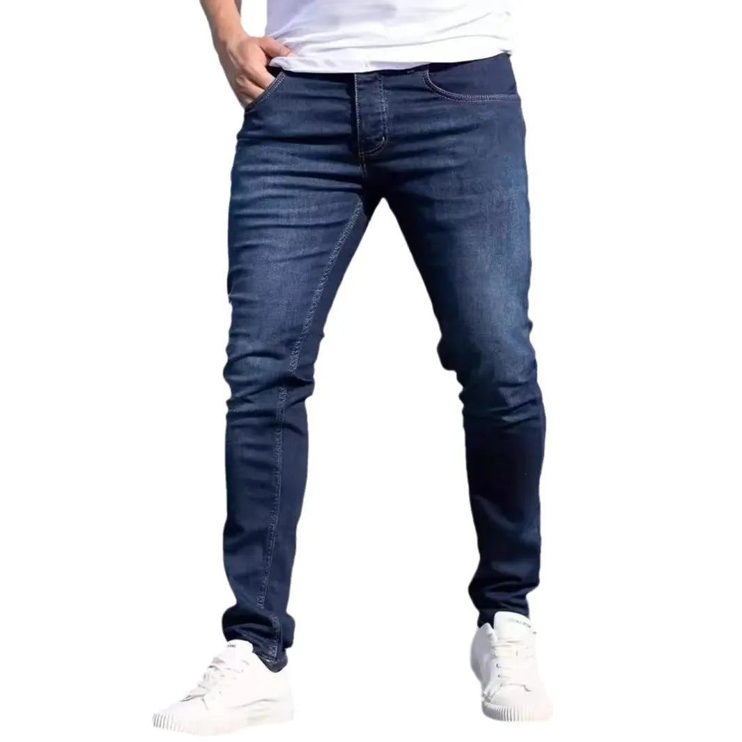 Man wearing dark blue slim-fit skinny jeans with a mid waist and zip fly.