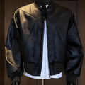 Man wearing a black slim-fit PU leather jacket with litchi grain texture and extended length.