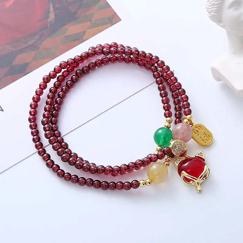 Purplish red garnet fox charm on an adjustable rope bracelet for women.