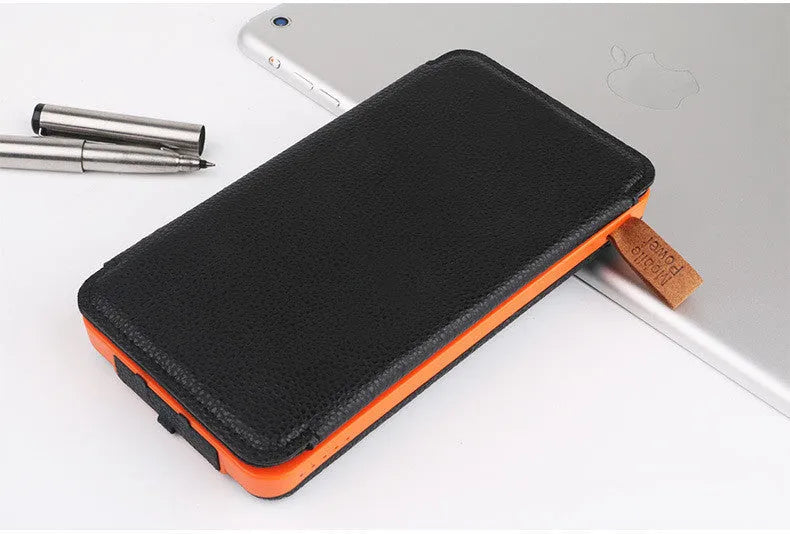 Black outdoor solar power bank with a solar panel and a built-in LED light displayed on a rock.