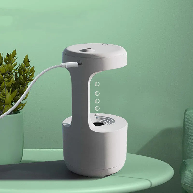 White columnar anti-gravity humidifier with LED clock display emitting mist on a wooden desk.