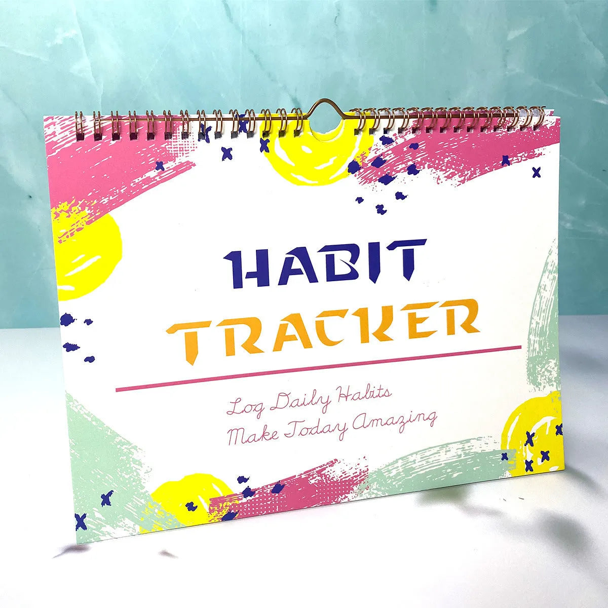 A4 habit tracking book with coloured cover open to show interior pages