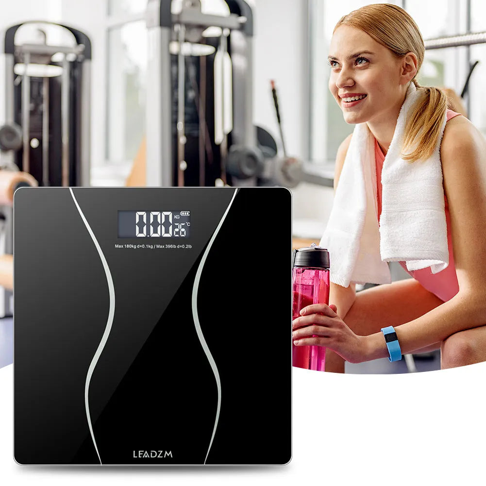 Black electronic digital bathroom scale on a hard floor, showing a weight reading on its display.