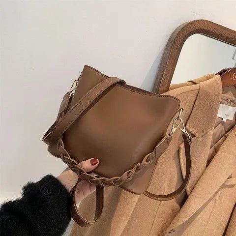 Khaki coloured PU leather one-shoulder crossbody bucket bag with woven detail on the front.