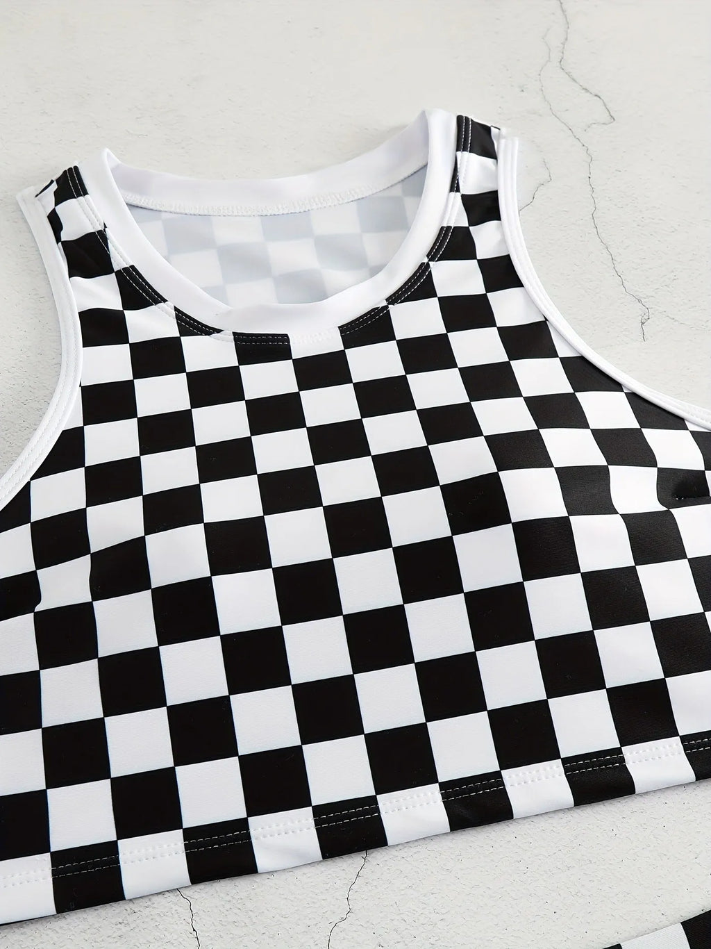 Women's backless racing one-piece swimsuit with suspenders in a black and white chessboard pattern.