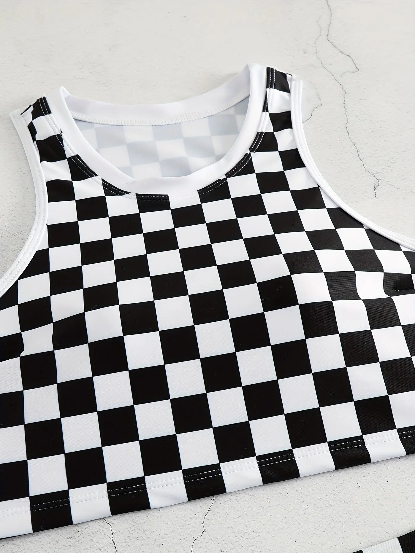 Women's backless racing one-piece swimsuit with suspenders in a black and white chessboard pattern.