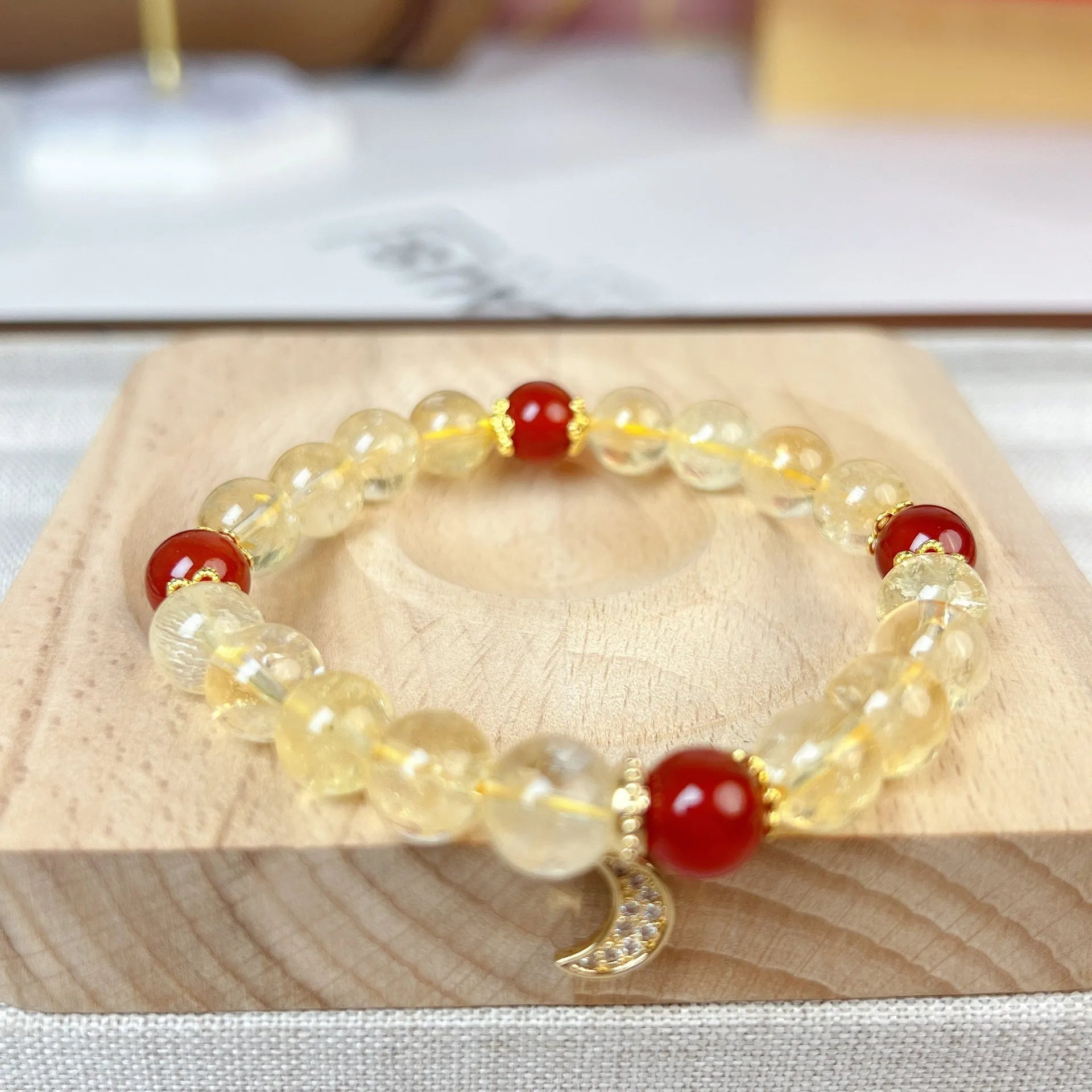 Citrine and red agate crystal moon boom bracelet for women on a white background.