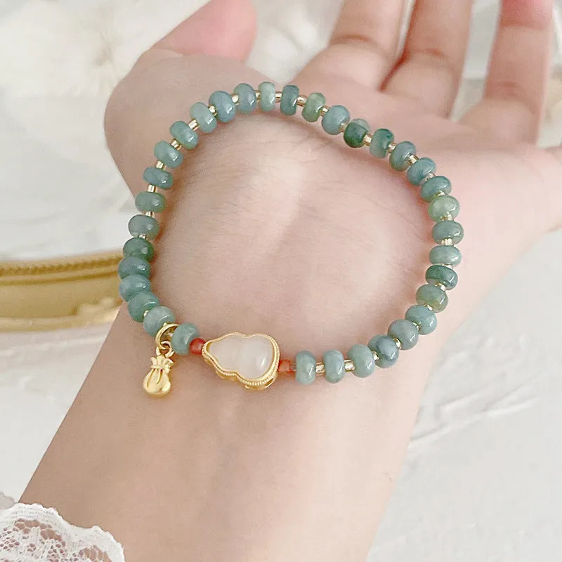 Women's jade bracelet with gourd shape, peace buckle charm, and strawberry quartz details in natural blue colours