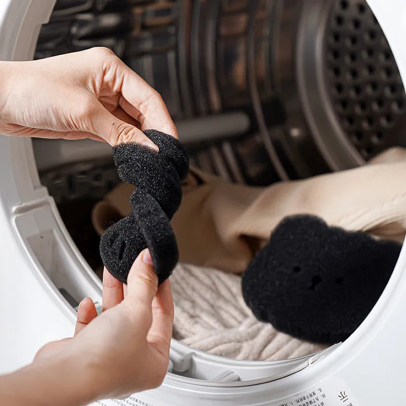 Two black bear-shaped sponge cleaning balls for pet hair removal in laundry