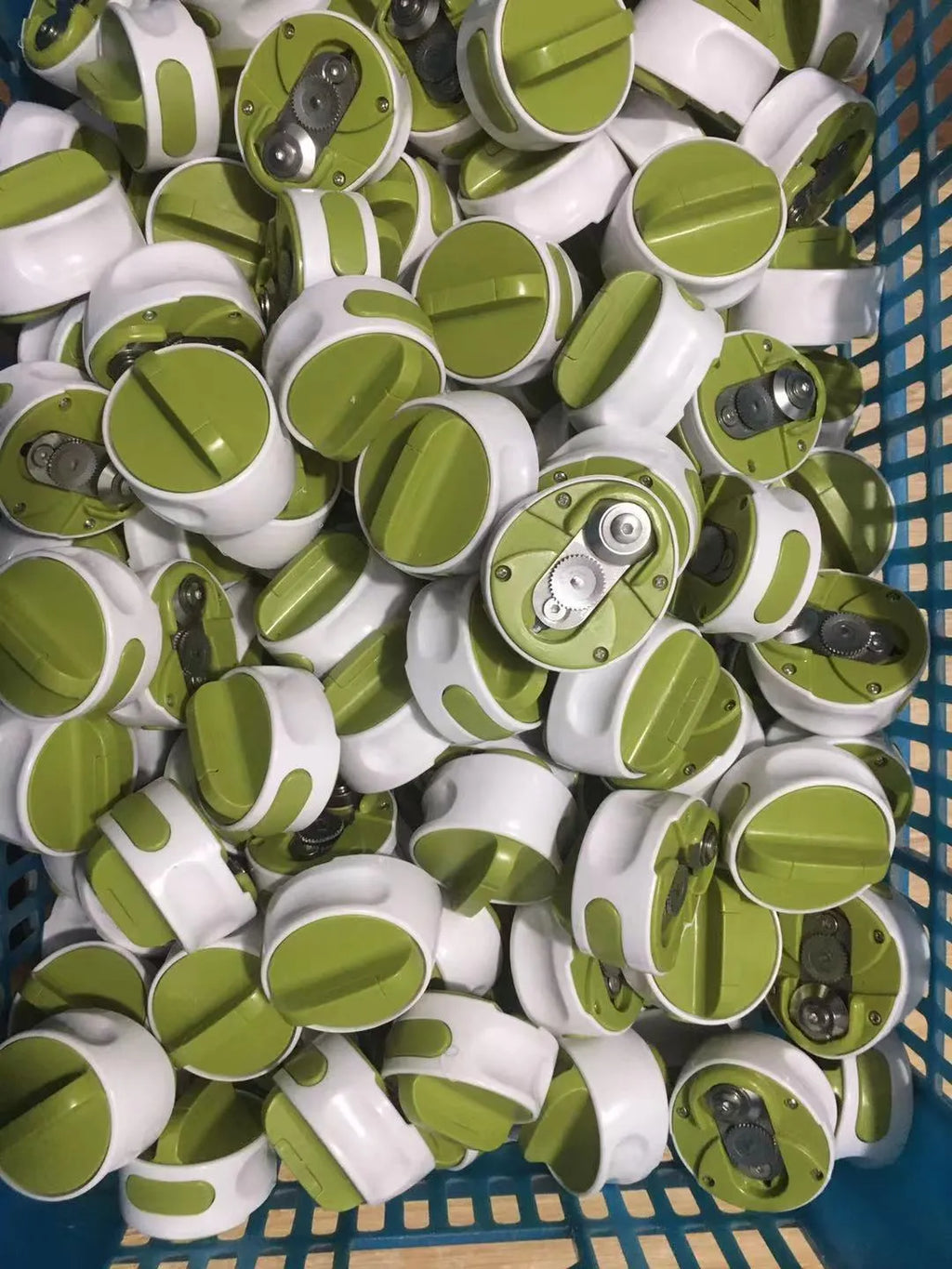 Green stainless steel bottle opener gadget for screw-top lids on a kitchen counter.