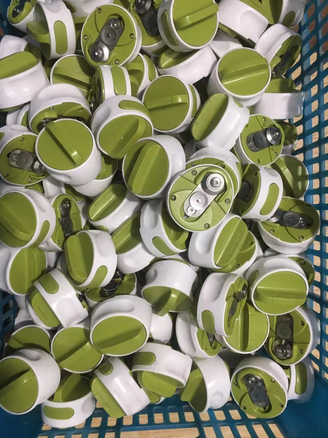 Green stainless steel bottle opener gadget for screw-top lids on a kitchen counter.