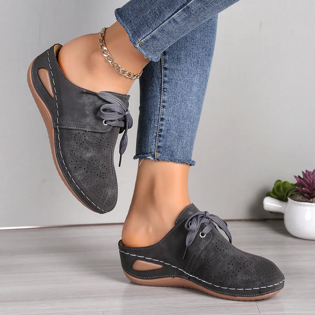 Women's black lace-up wedge slippers with hollow-out design, suede upper, and rubber sole.