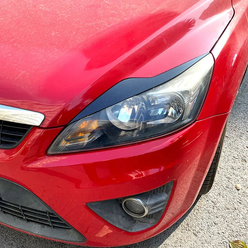 Two ABS plastic headlight eyebrow stickers for Ford Focus in carbon fibre and piano black finishes.