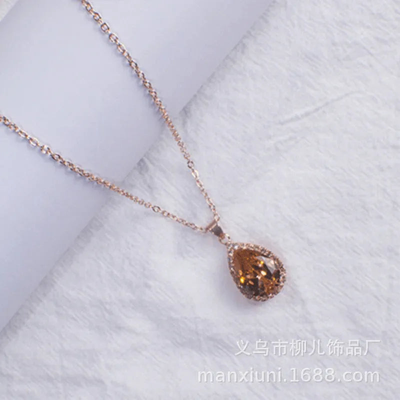 Close-up of a rose gold tone drop shape necklace with rhinestone details on a geometric pendant.