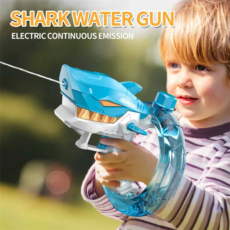 Blue Shark-shaped electric water gun toy with a large tank, placed on a sandy beach.