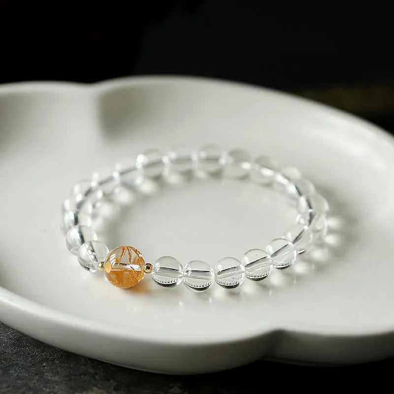 Geometric obsidian and white crystal bracelet with a golden dragon charm on a wrist.