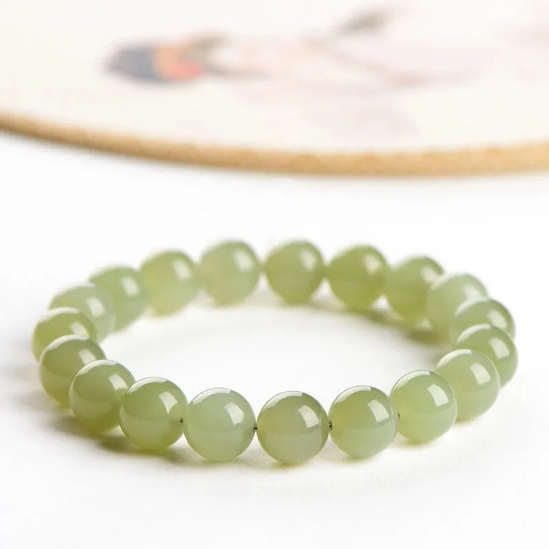 Unisex Hetian Jade ball bracelet with polished beads in clear colours on a wrist.