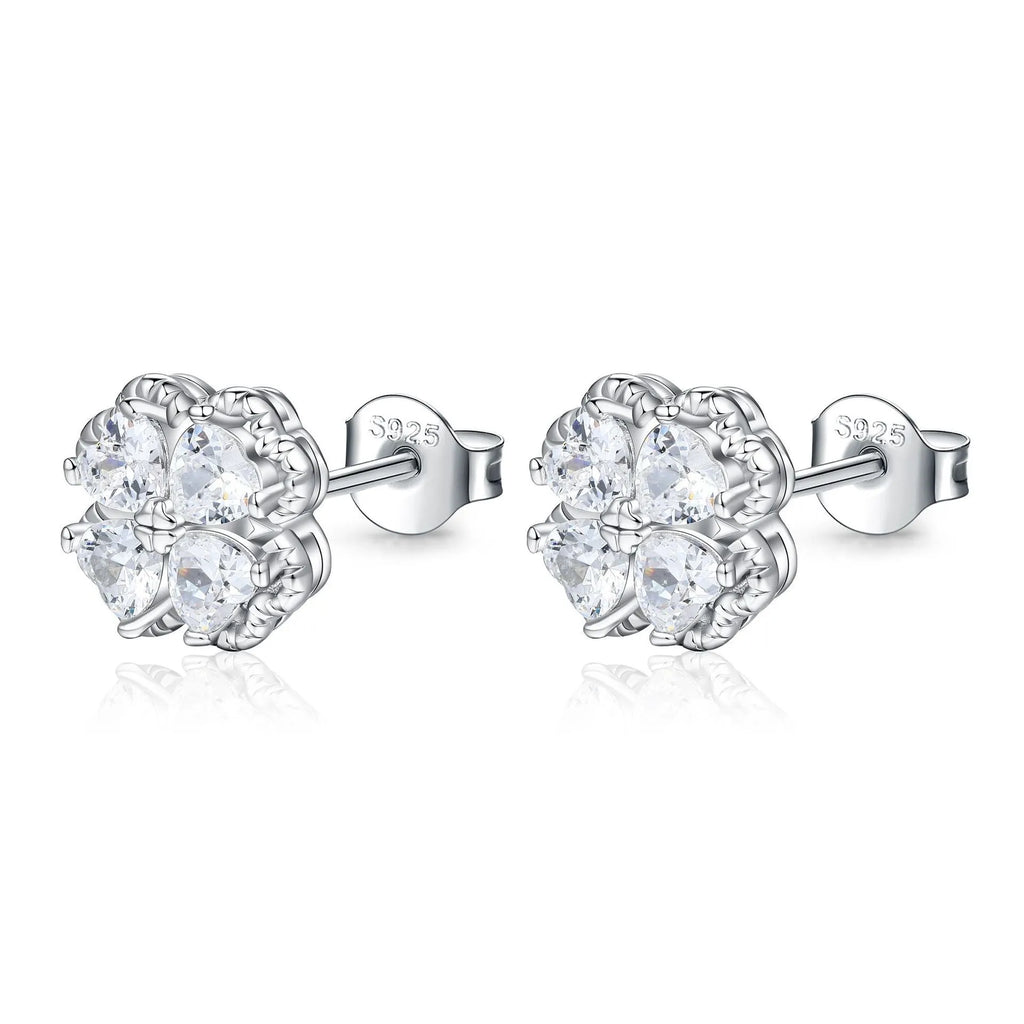 Close-up of a pair of heart-shaped 925 silver earrings with a four-leaf clover charm and zircon stones, in white gold colour.