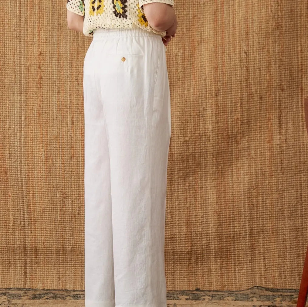 Woman wearing loose-fit linen trousers with a high elasticated waist in a straight-leg cut.