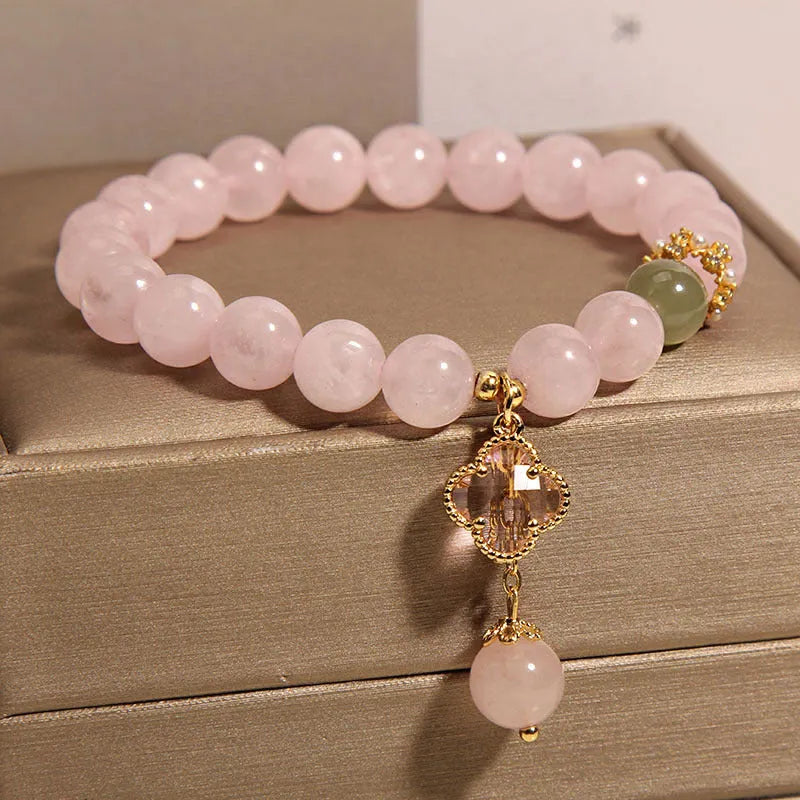 Pink crystal bracelet with four-leaf clover pendant and rhinestone details on women's wrist