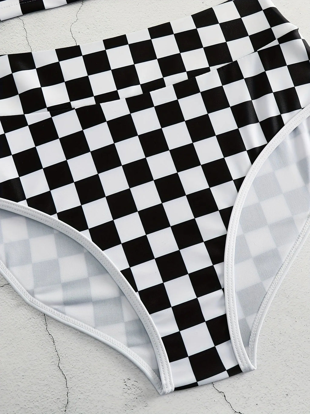 Women's backless racing one-piece swimsuit with suspenders in a black and white chessboard pattern.