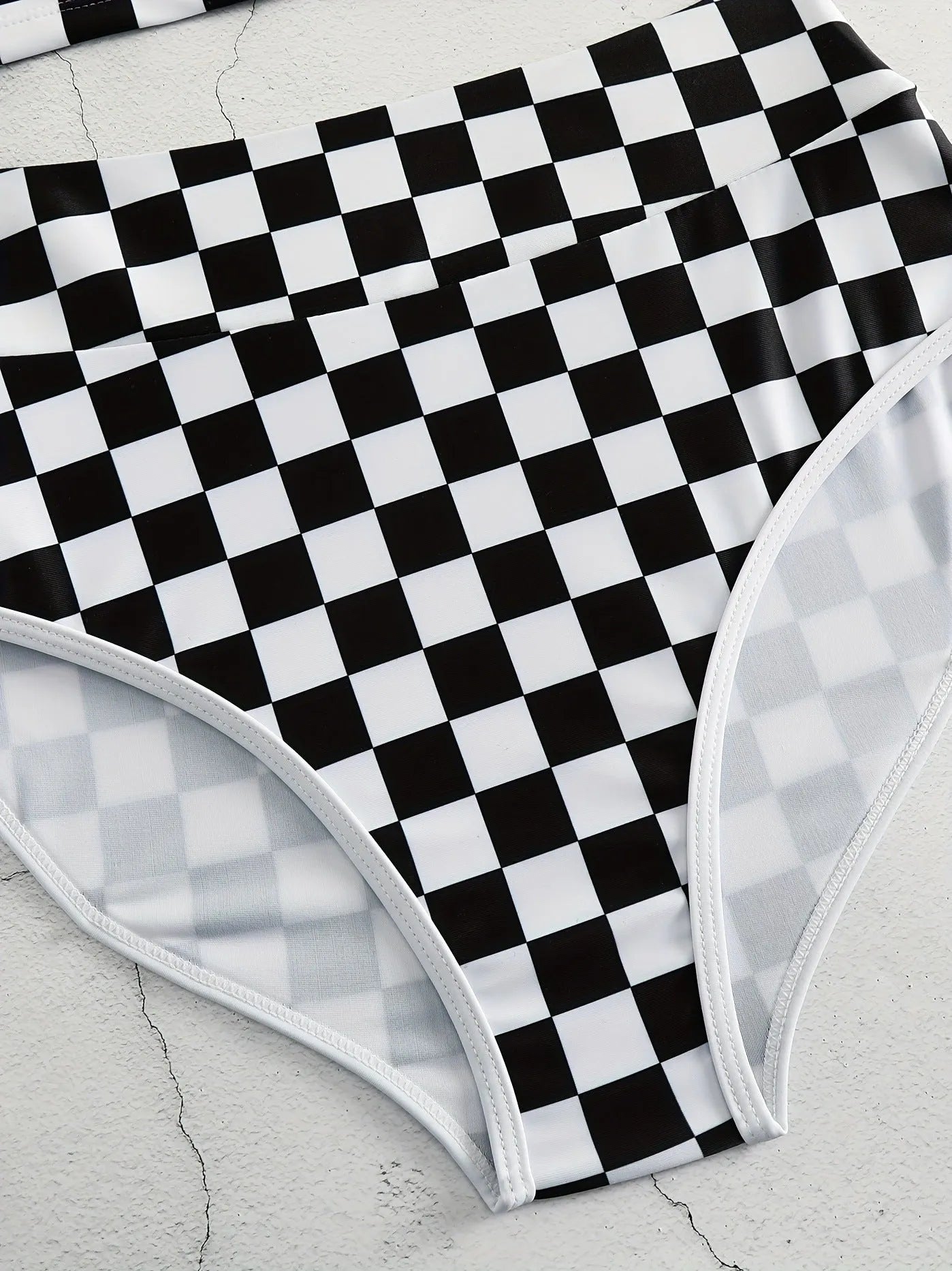 Women's backless racing one-piece swimsuit with suspenders in a black and white chessboard pattern.