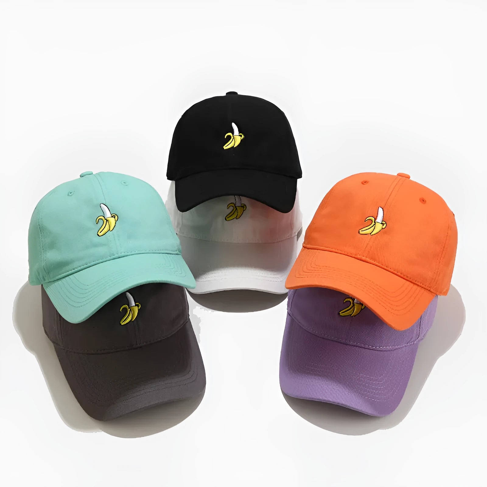 Adjustable banana-embroidered baseball cap in soft polyester fabric, shown in multiple colours.