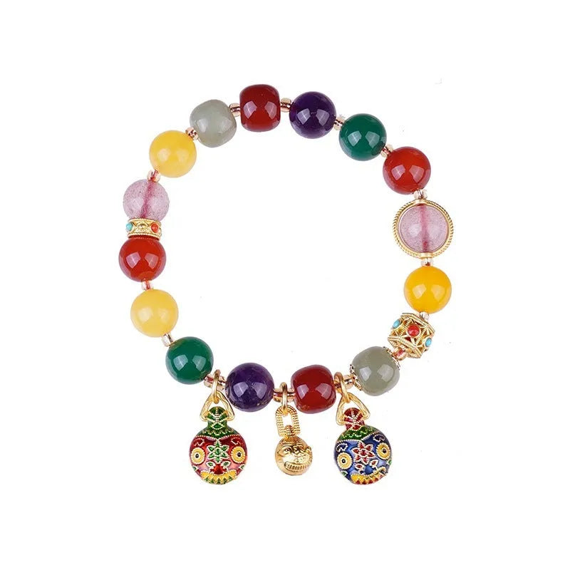 Close-up of a bracelet with a hand-woven gold beast charm and large brown agate beads.