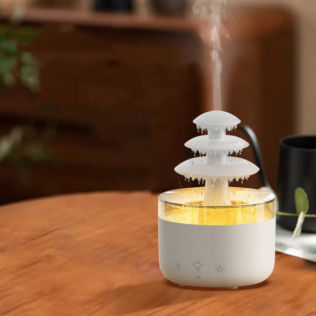 White cloud-shaped USB humidifier and essential oil diffuser with colourful mood lights on a wooden table.