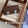 Women's sterling silver earrings with heart-wrapped oval blue diamond centrepiece on silver geometric design