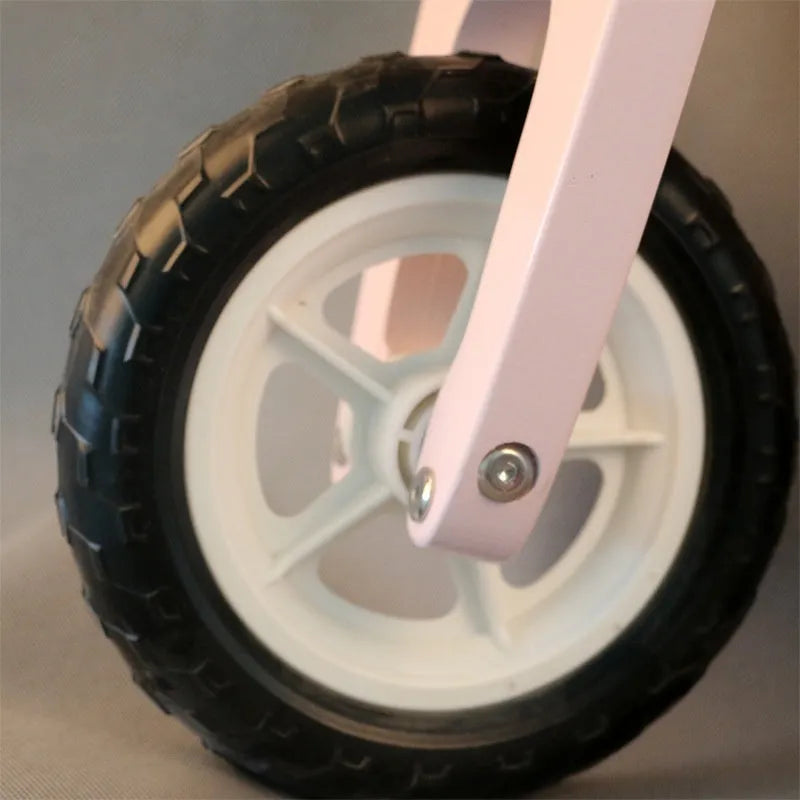A pink wooden balance scooter for toddlers and children with a 10-inch deck.