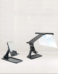 Black folding mobile phone screen magnifier with detachable holder on a desk.