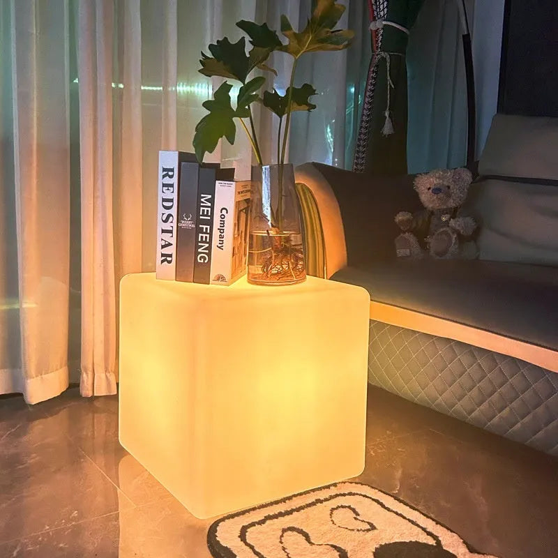 A modern, square white LED cube light functioning as a waterproof outdoor stool.