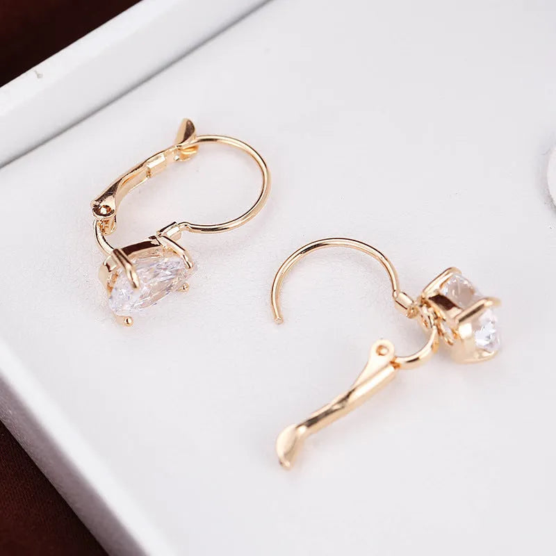 Gold and platinum drop earrings with a cubic zirconia stone set in a simple metal design.