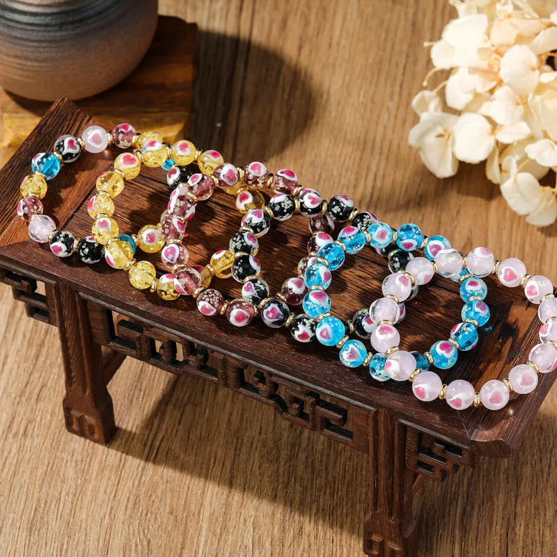 Handmade glass bracelet with swallowing gold beast design and cherry blossom heart in six colours.