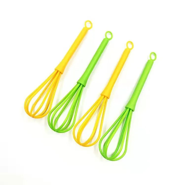 Plastic creative mini manual eggbeater in green and yellow, size 4x18.5 cm, on kitchen counter