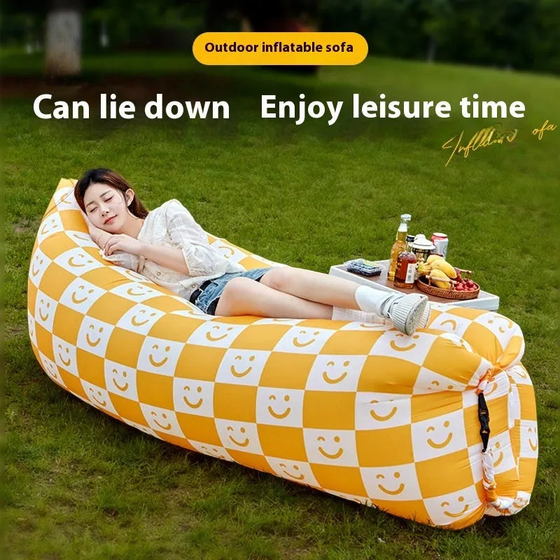 Inflatable portable sofa in a colourful design, shown folded to its 36cm by 27cm size and in use outdoors.
