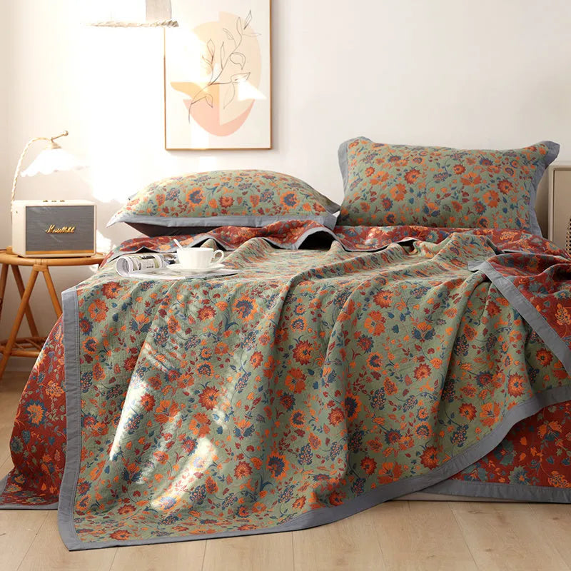 Cotton gauze bed blanket set with floral pattern and two matching pillowcases laid on a bed