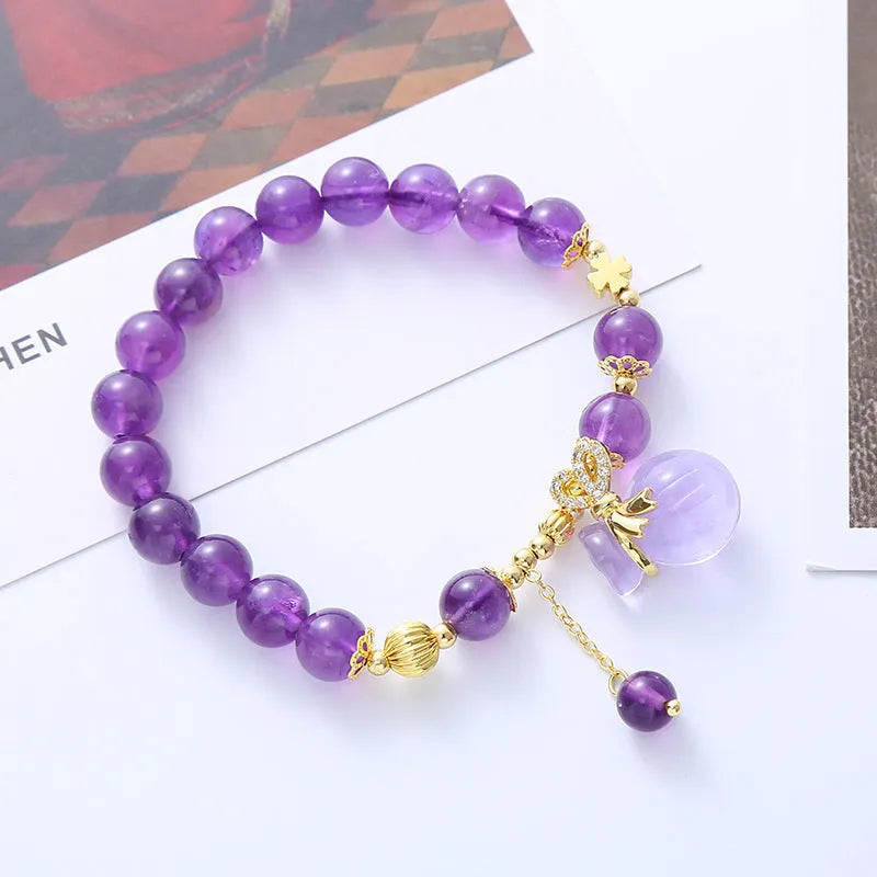 Purple crystal bracelet with ethnic money bag pendant and peace buckle closure on wrist