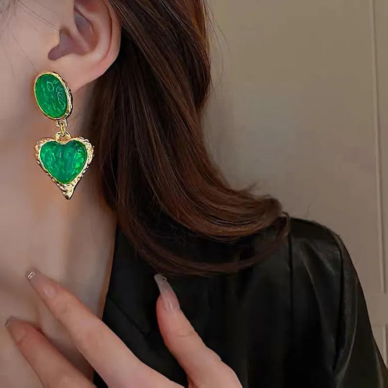 Oval heart-shaped alloy stud earrings with silver pleated edge, shown in purple, red, green, and yellow/white colour options.
