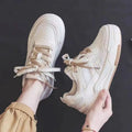 Women's beige and pink low-top rubber sole sneakers on a white background