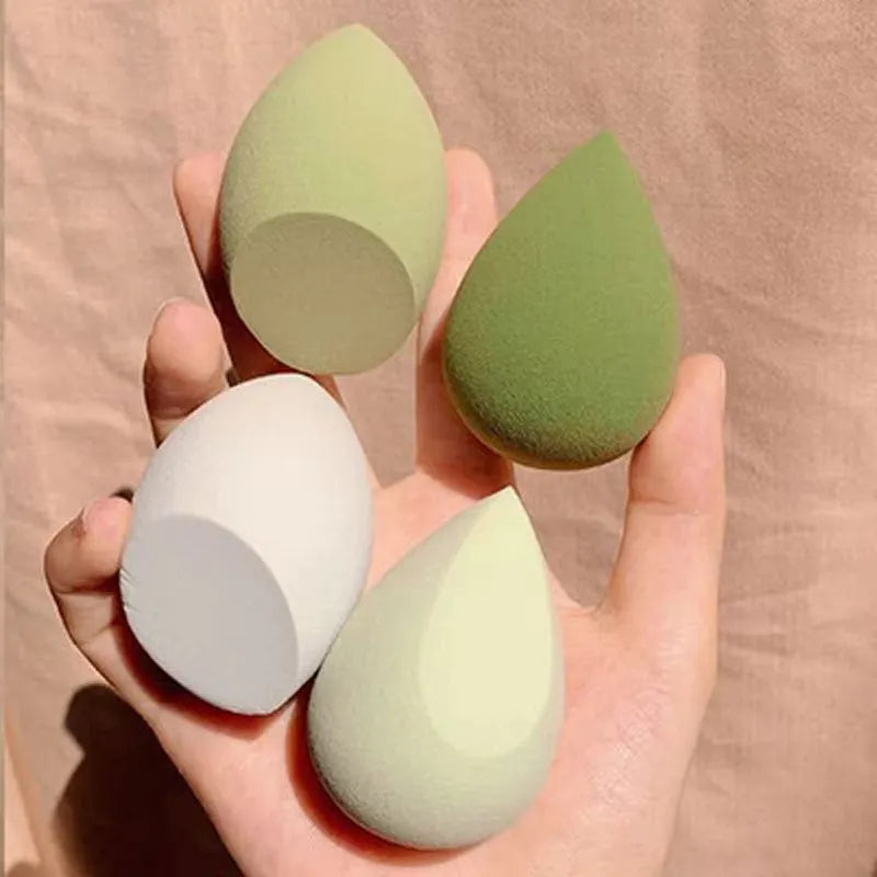 Set of seven differently shaped makeup sponges in various colours on pink background