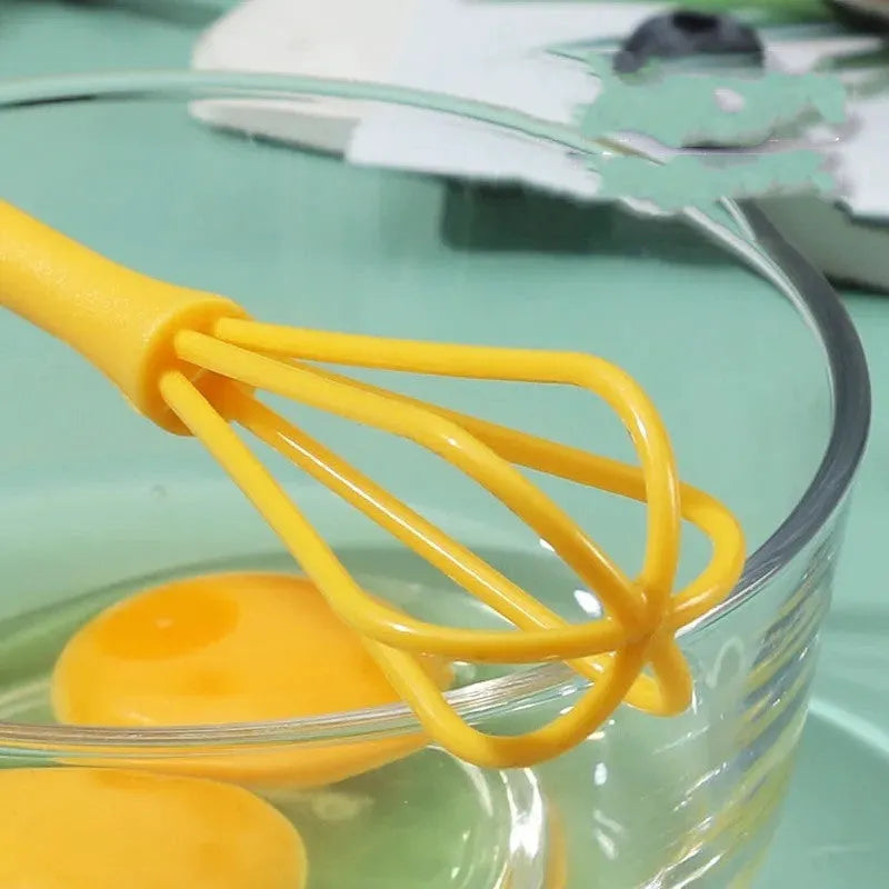 Plastic creative mini manual eggbeater in green and yellow, size 4x18.5 cm, on kitchen counter