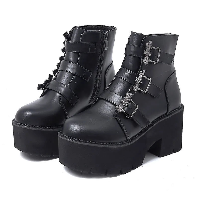 Black women's punk ankle boots with bat buckle and side zip on a thick sole.