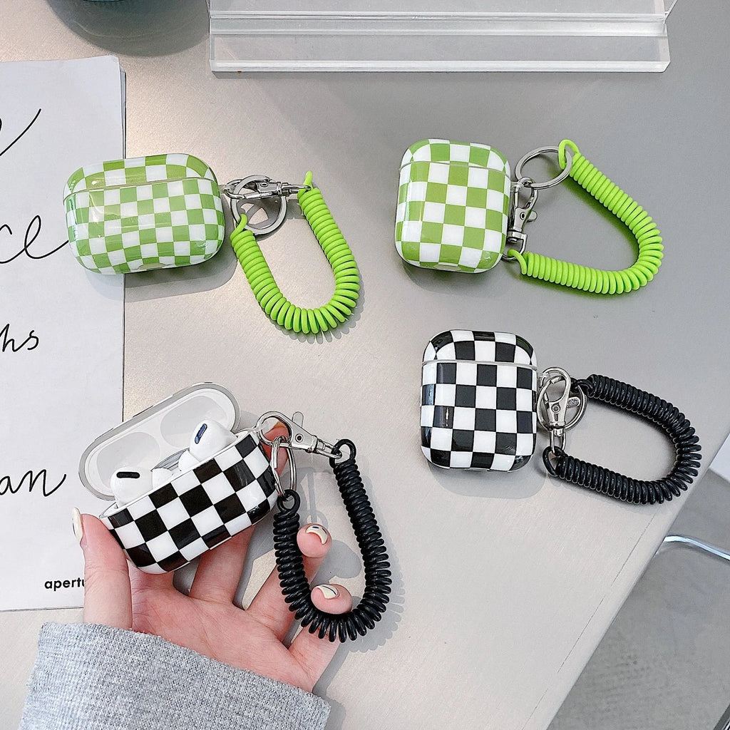 Black and green checkerboard pattern TPU protective case for Apple AirPods, shown with an optional attached lanyard.