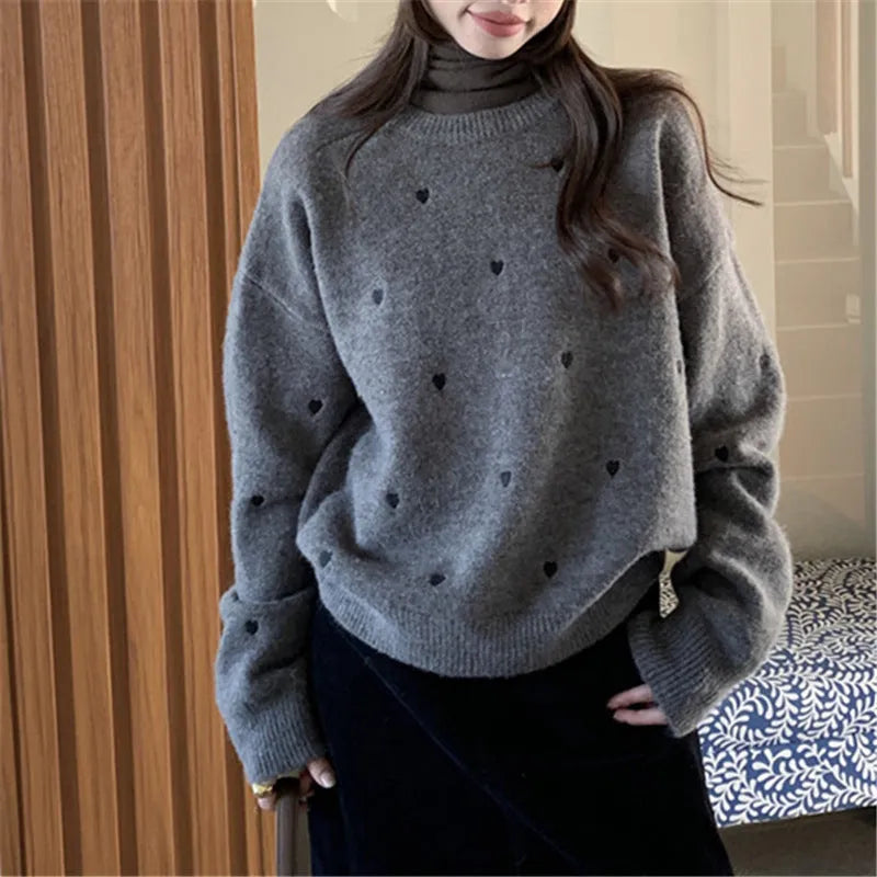 Women's loose grey acrylic pullover sweater with embroidery on the front.