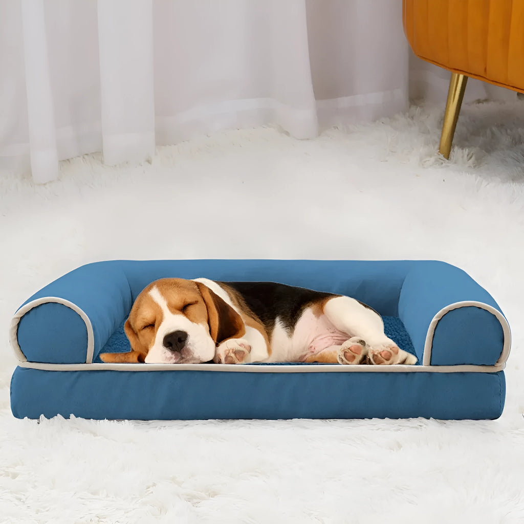 Square sponge dog bed in blue cloth, showing its raised breathable design on a wooden floor.